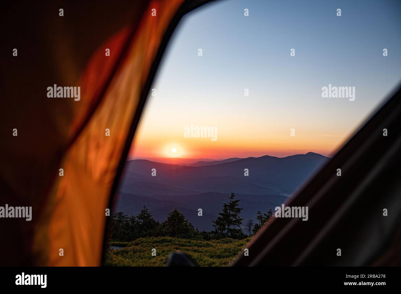 Sonnenaufgang von einem Zelt in den Bergen aus gesehen. Die Sonne geht über Babia Gora auf - dem höchsten Berg in den Zywiecki Beskiden Stockfoto