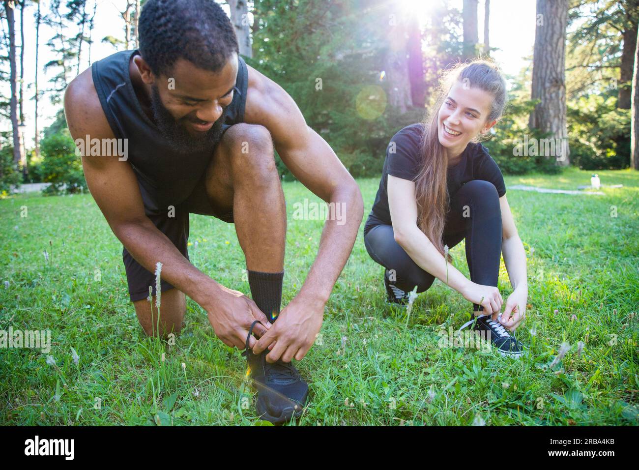 Zwei Sportler binden ihre Schuhe beim Workout in einem Park zusammen Stockfoto