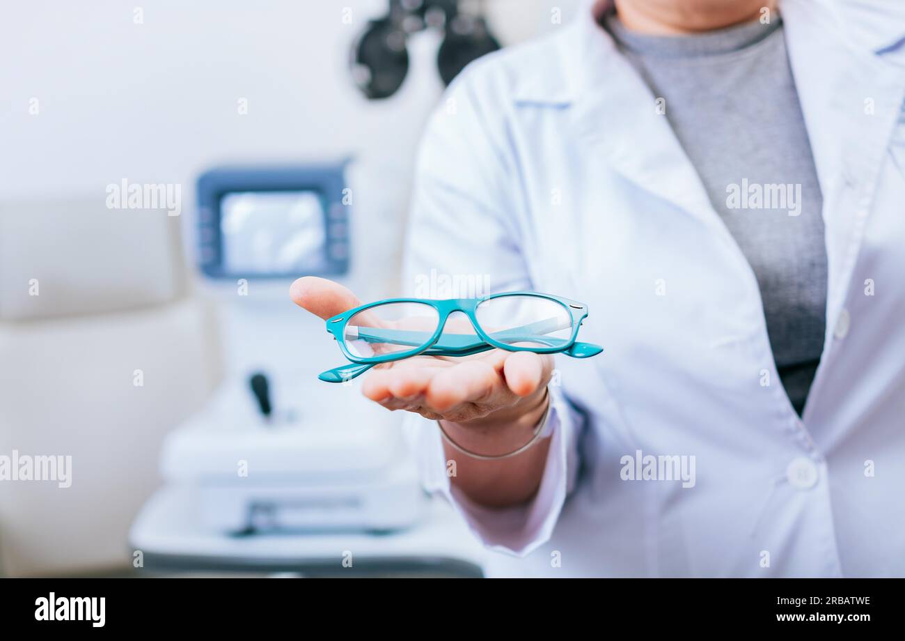 Optiker-Hände zeigen eine Brille. Augenarzt gibt Brille in Handfläche. Brille und visuelles Gesundheitskonzept Stockfoto