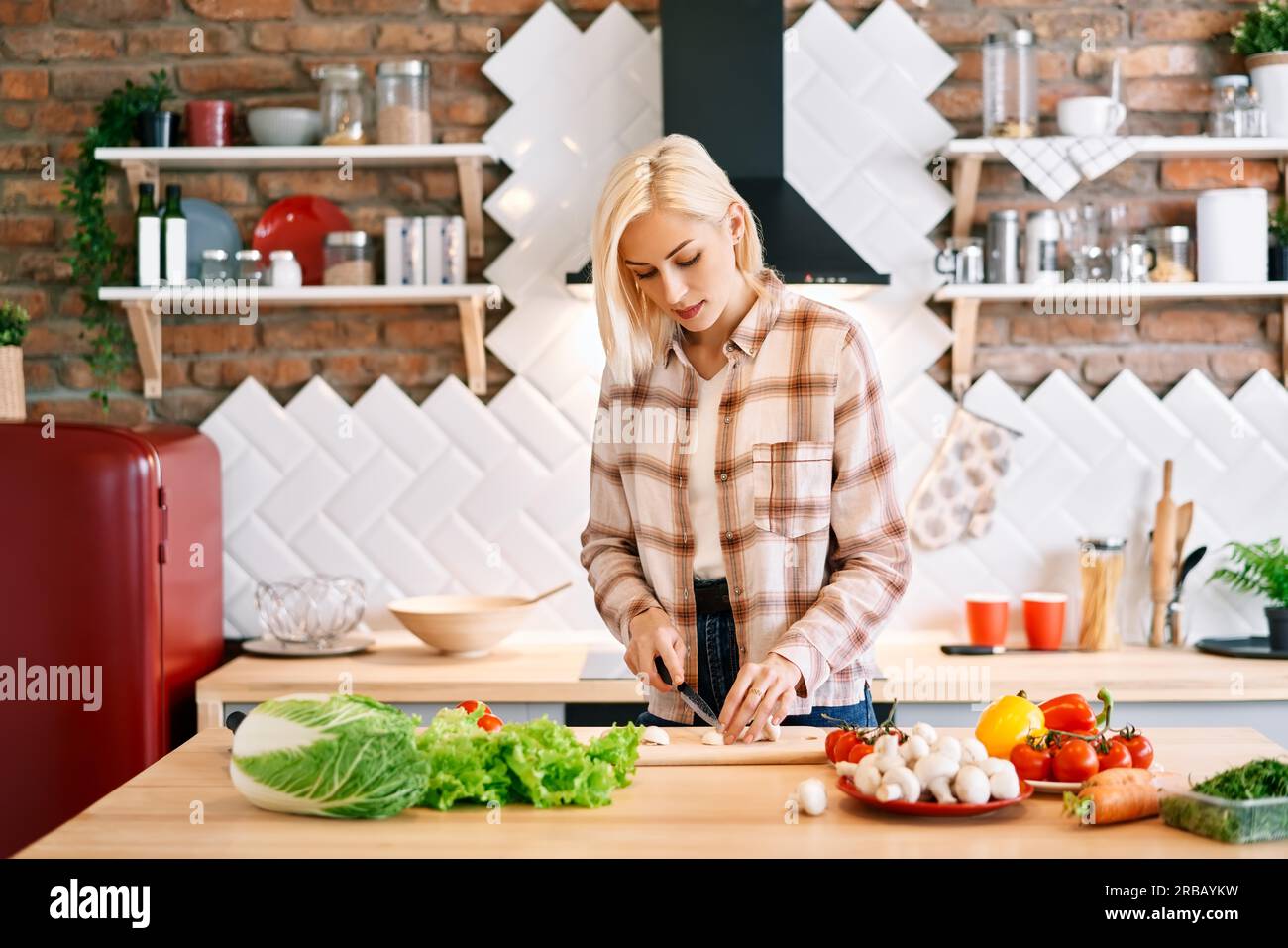 Lächelnde junge Frau, die in der Küche zu Hause gesundes Essen kocht. Vegane Ernährung Lebensmittelkonzept Stockfoto