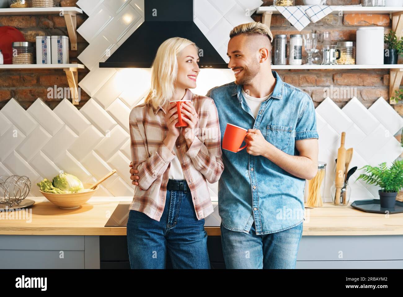 Junge glückliche Paar trinken Kaffee am Morgen und genießen die Gesellschaft von einander in der Küche zu Hause. Beziehung, Familienkonzept Stockfoto