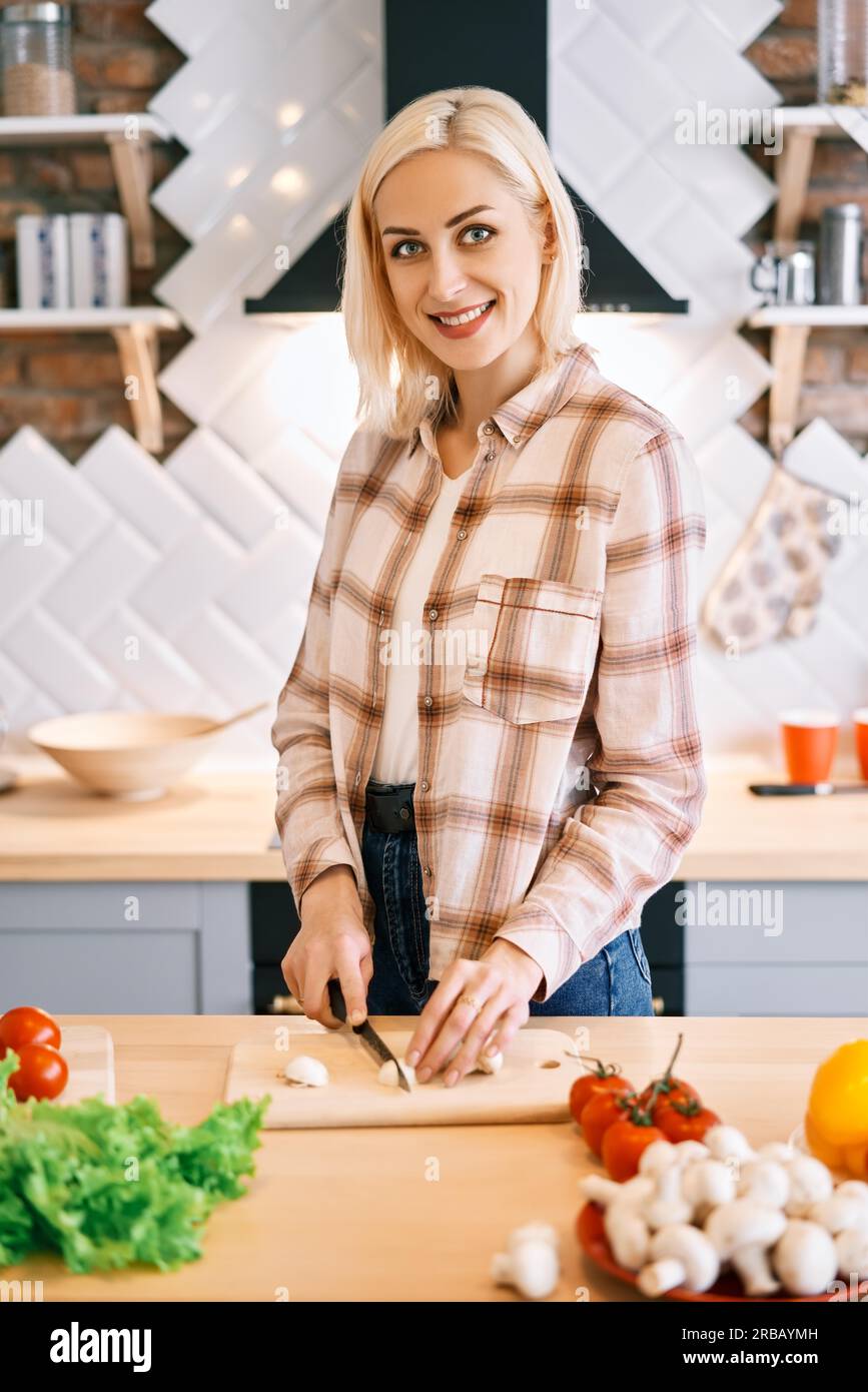 Lächelnde junge Frau, die in der Küche zu Hause gesundes Essen kocht. Vegane Ernährung Lebensmittelkonzept Stockfoto