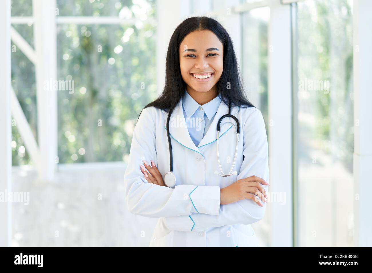 Lächelnde afroamerikanische Ärztin mit gekreuzten Armen im Krankenhaus. Medizin, Beruf und Gesundheitskonzept Stockfoto