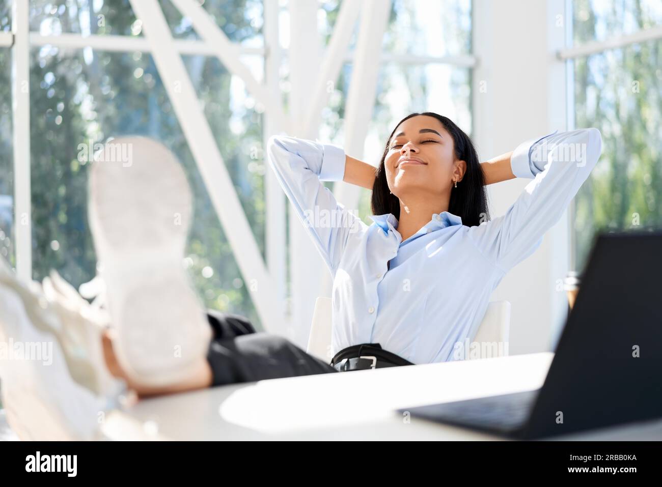 Attraktive afroamerikanische Geschäftsfrau, die sich im modernen Büro ausruhen und Freizeit genießen kann. Entspannungskonzept. Pausenzeit Stockfoto
