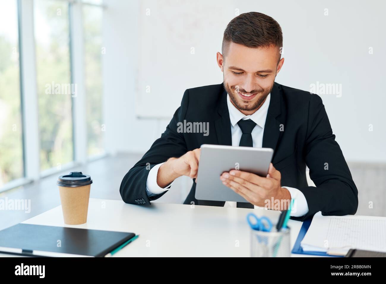 Glücklicher erfolgreicher Geschäftsmann in eleganter Suite mit Tablet sitzen in modernen kreativen Büro. Business-Konzept Stockfoto