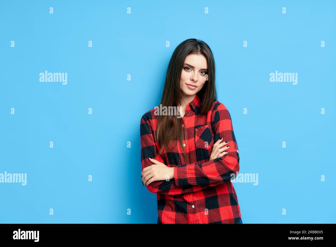 Ziemlich zuversichtlich junge schöne Frau in lässiger Kleidung mit gekreuzt Arme blicken auf die Kamera auf blauem Hintergrund Stockfoto