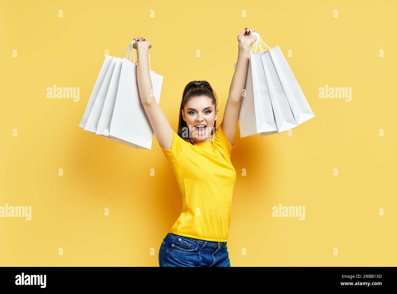 Glücklich aufgeregt shopaholic Frau mit Einkaufstaschen in den Händen genießen Ihr Einkauf auf gelbem Hintergrund Stockfoto