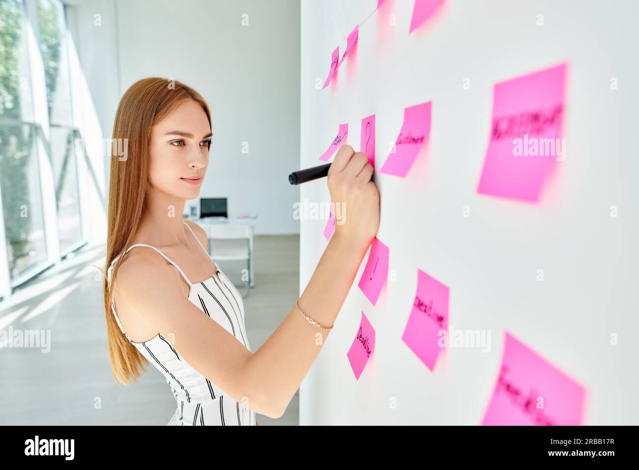 Attraktive konzentrierte Geschäftsfrau mit Haftnotizen zu schreiben und Ideen im kreativen Büro zu teilen. Business, Menschen, Teamarbeit und Planungskonzept Stockfoto