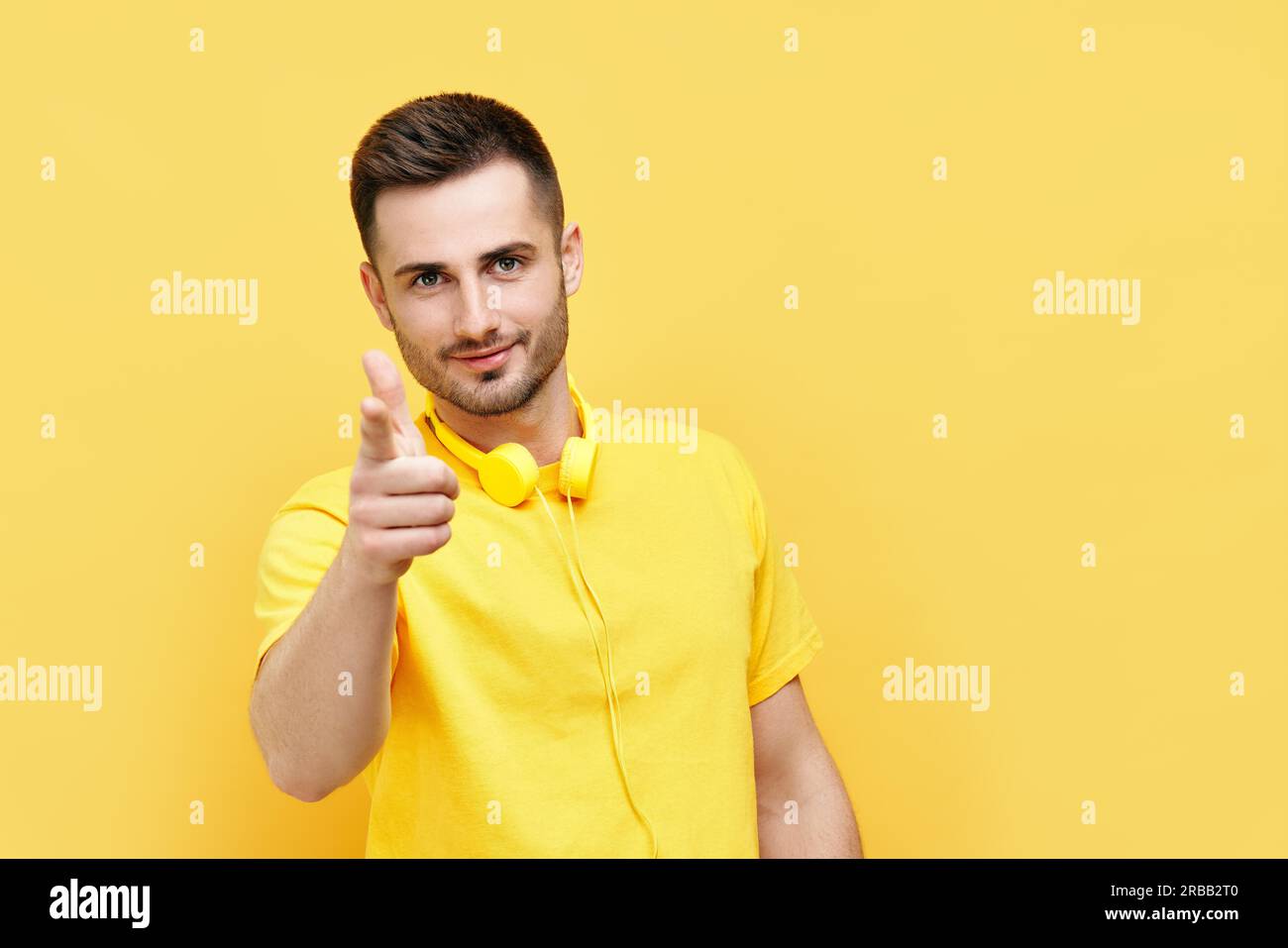 Hübscher junger Mann, der auf Sie zeigt und auf gelben Hintergrund mit Kopierraum zur Kamera schaut. Auswahlkonzept Stockfoto