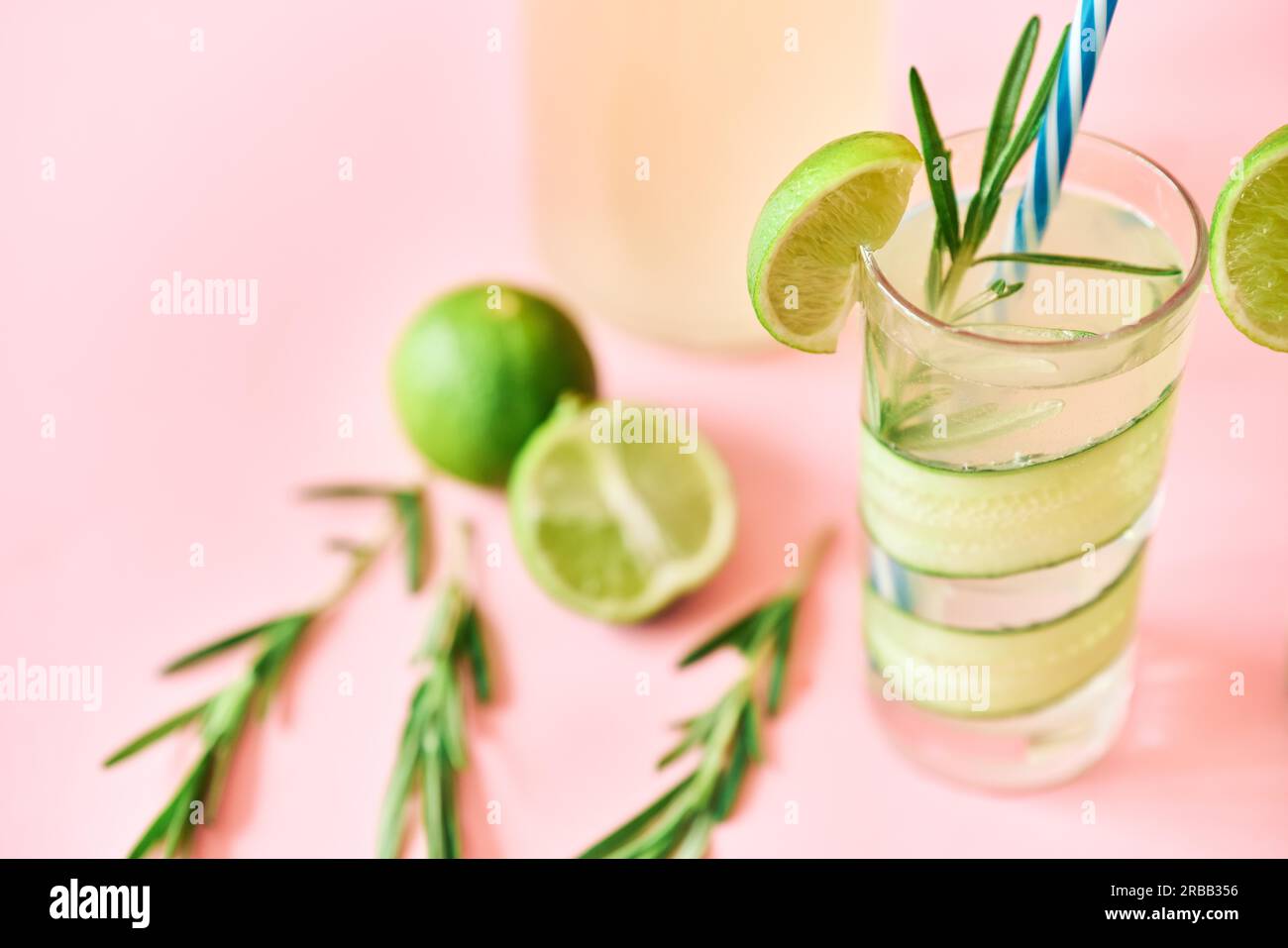 Kalter erfrischender Cocktail mit Limette, Gurke, Rosmarin und Eis im Glas auf rosa Hintergrund aus nächster Nähe. Party, Sommerkonzept Stockfoto