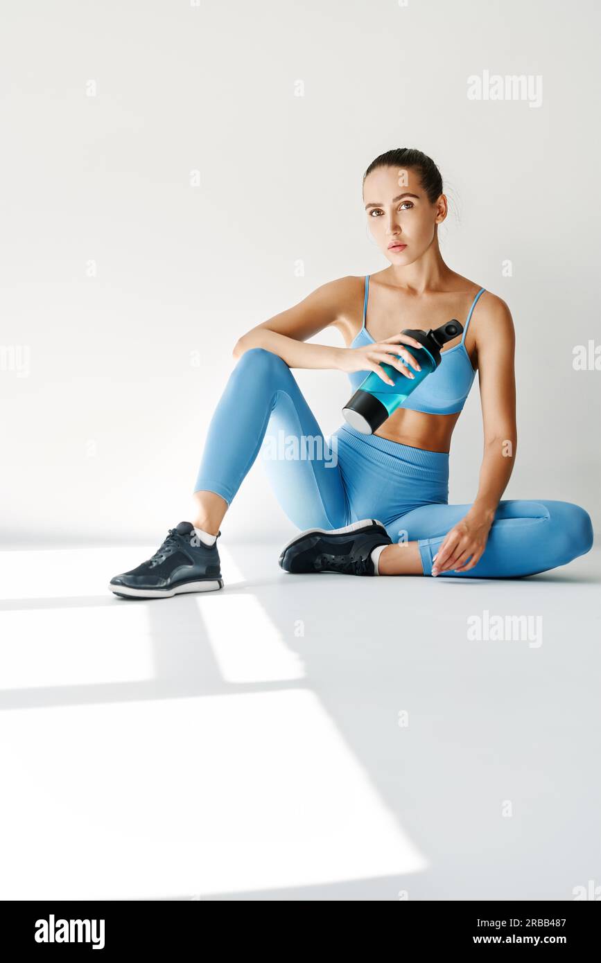 Junge Fitness-Frau entspannen sich auf dem Boden mit einer Flasche Wasser nach dem harten Training. Sportkonzept Stockfoto