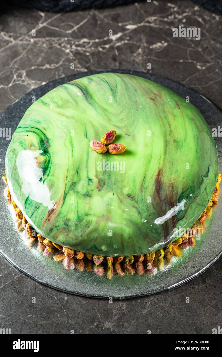 Gourmet Pistachio und Strawberry Entremet Cake mit mehrlagigem Schwammkuchen, Pistaziengelee, Erdbeergelee und Erdbeermousse, im Spiegel bedeckt Stockfoto