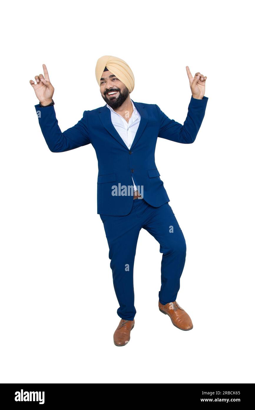 Ein fröhlicher indischer sikh-Geschäftsmann im Anzug, der isoliert auf weißem Hintergrund Bhangra tanzt. Unternehmenskonzept. Stockfoto