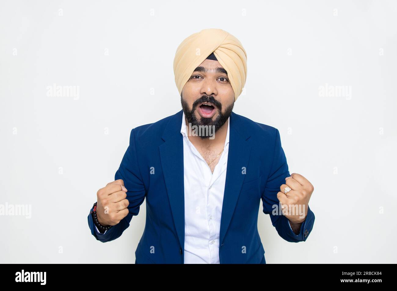 Aufgeregter junger indischer sikh-Mann in blauem Anzug und Turban-Schreien isoliert auf weißem Hintergrund. Stockfoto