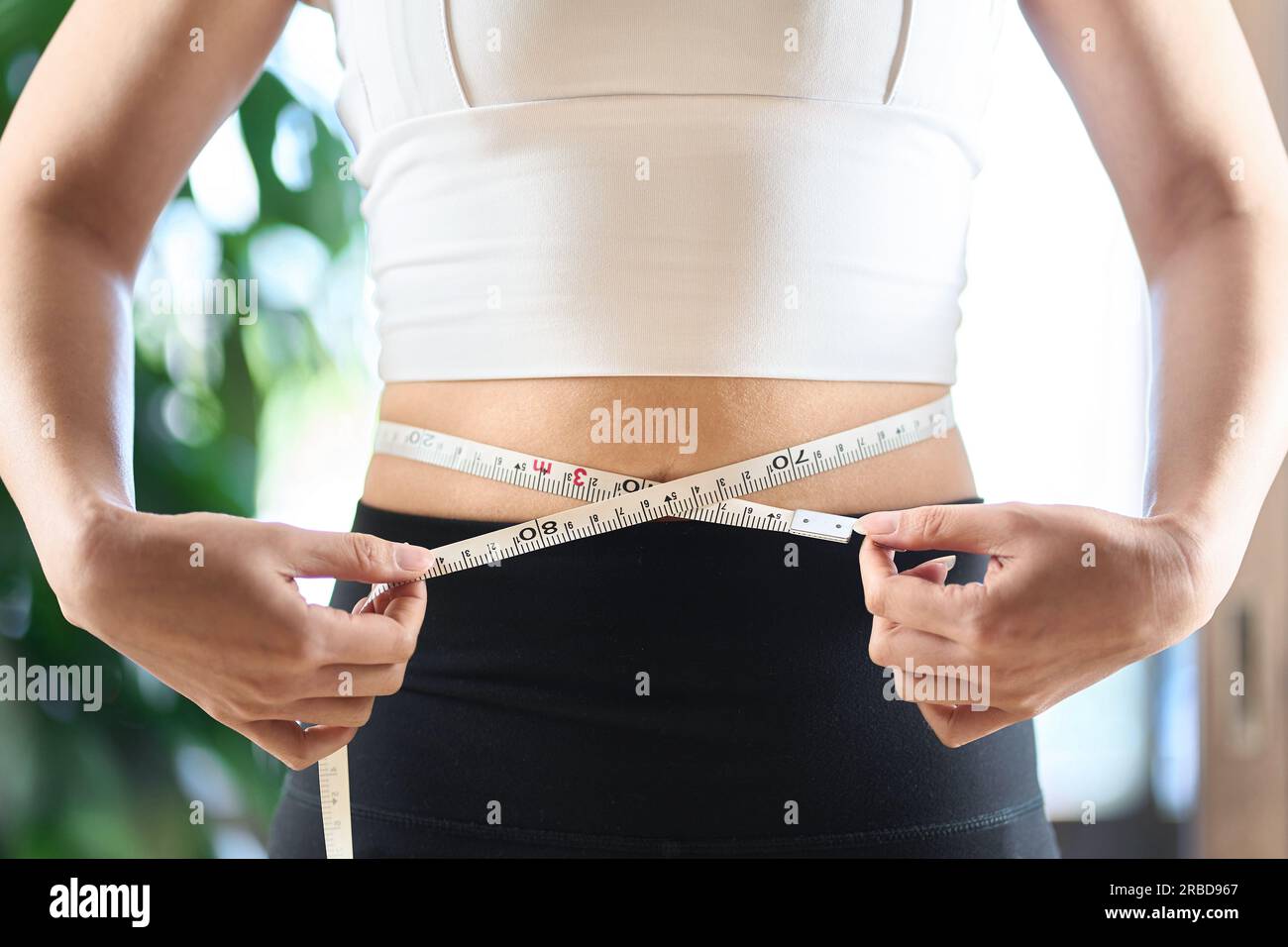 Asiatische Frau, die ihre Taillengröße mit einem Maßband misst Stockfoto