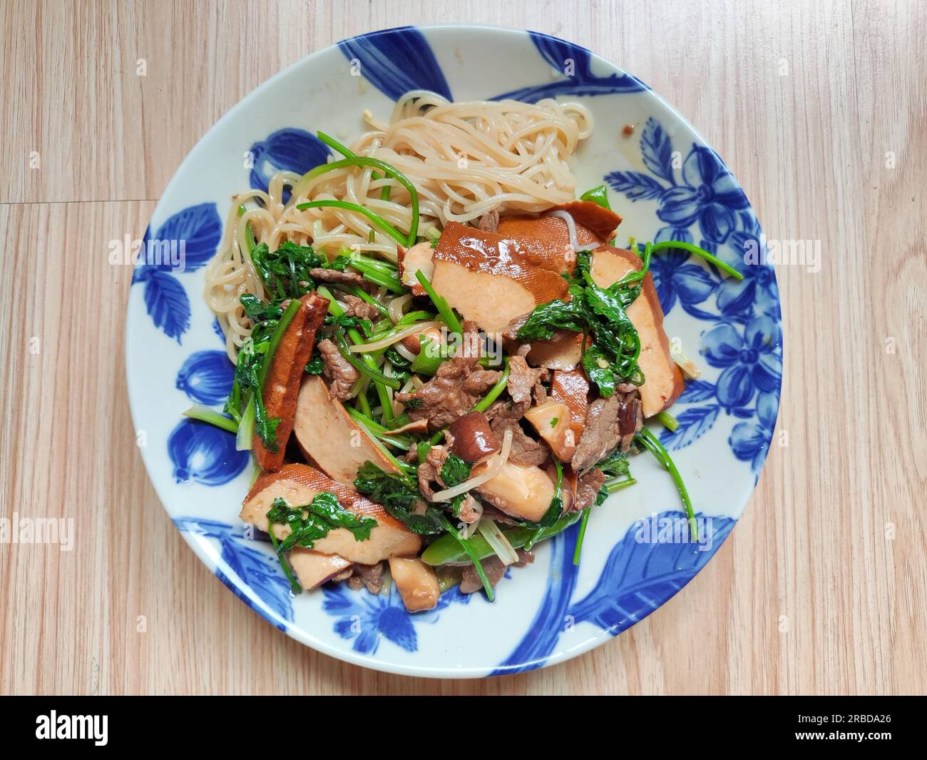 Rinderbraten mit grünem Gemüse und Bohnenquak auf den Nudeln auf dem blauen Gericht Stockfoto