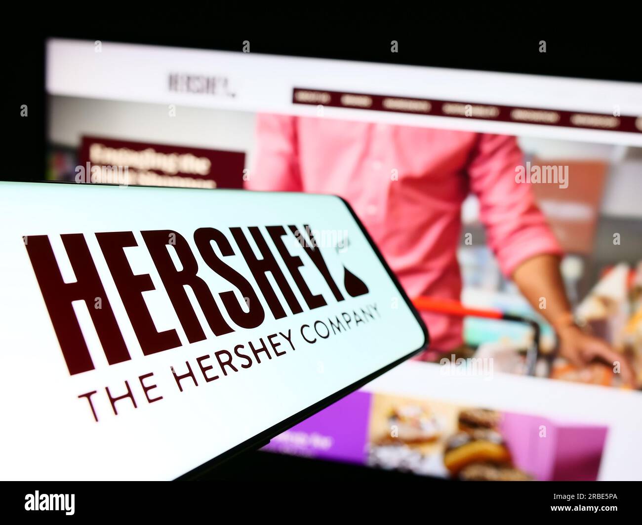 Smartphone mit Logo des amerikanischen Lebensmittelgeschäfts The Hershey Company auf dem Bildschirm vor der Website. Fokus auf die Mitte links des Telefondisplays. Stockfoto