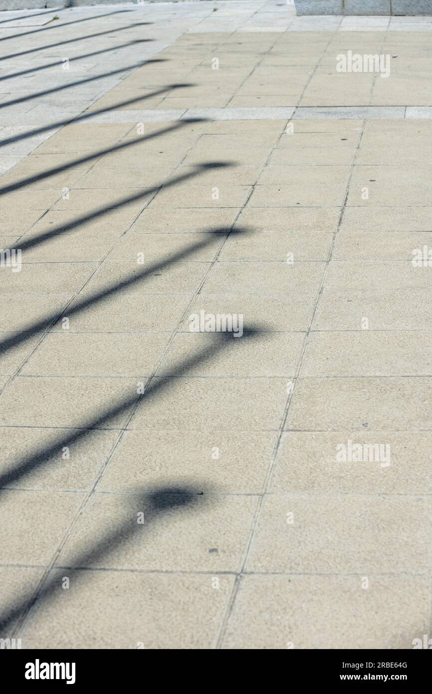 Lange schwarze Schatten von Pfosten auf dem gefliesten Boden Stockfoto