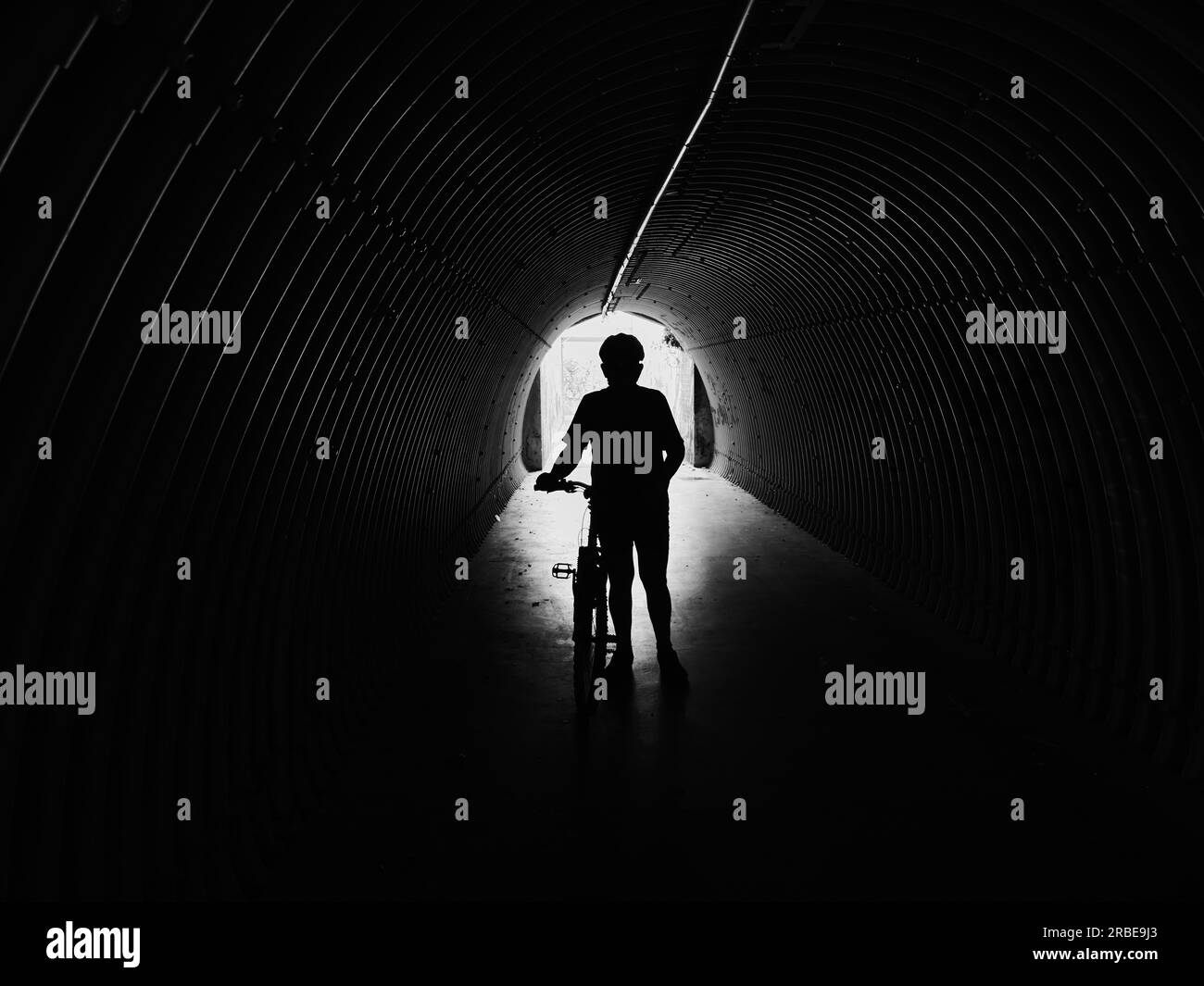 Ein erstaunliches Foto einer Silhouette eines Mannes, der mit einem Mountainbike in der Unterführung steht Stockfoto