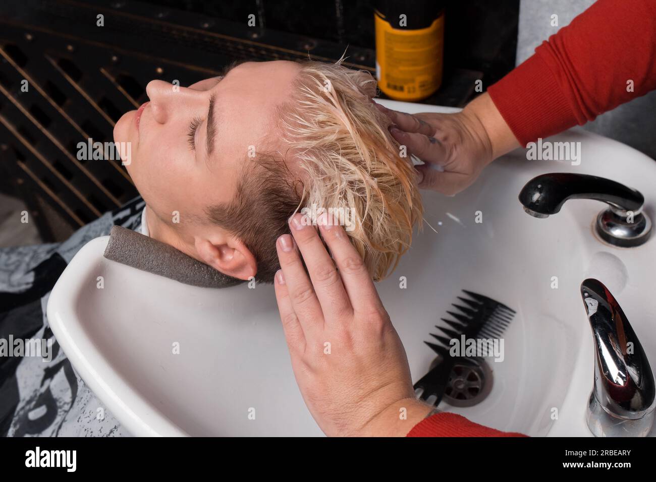 Die Hände des Friseurs massieren den Kopf des Kunden, nachdem er sich die Haare gewaschen hat, bevor er den Friseur geschnitten hat. Stockfoto