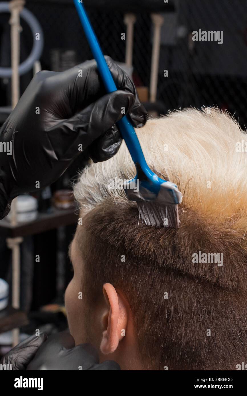 Nahaufnahme, Kopfhaar, das weiß mit einer Bürste in einem Friseursalon malt, männliche Schönheit und Pflege. Stockfoto