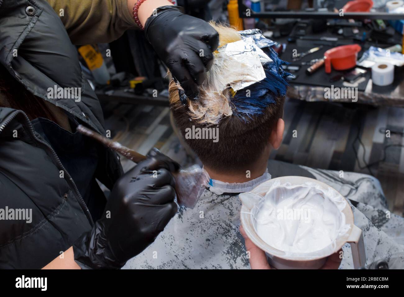Der Prozess der Männerfarbe Styling modische Haarfarbe durch einen professionellen Friseur bei der Arbeit. Stockfoto