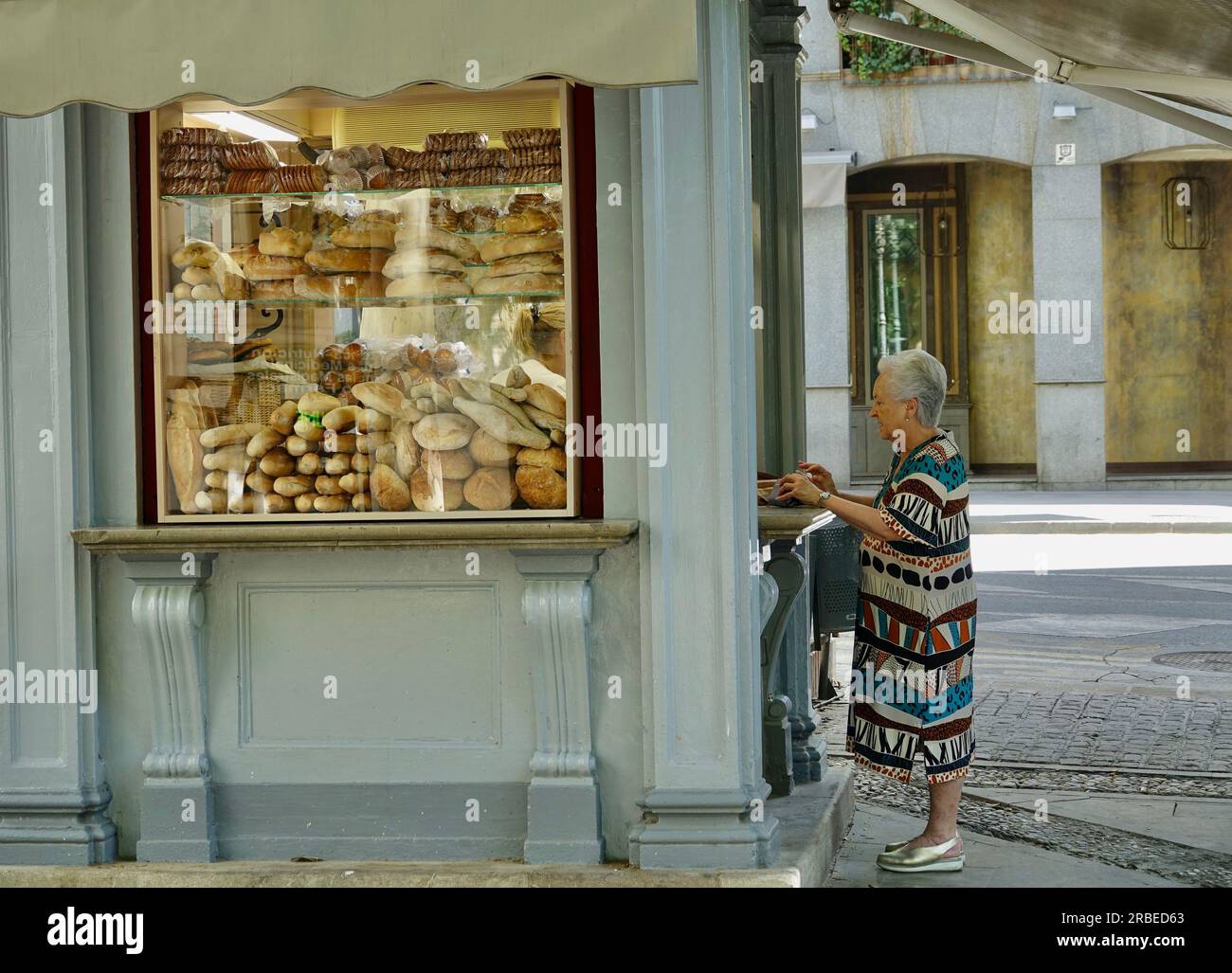 Granada, Spanien; 08. Juli 2023: Eine ältere Frau kauft Brot in einem Straßencafé in Granada (Spanien) Stockfoto