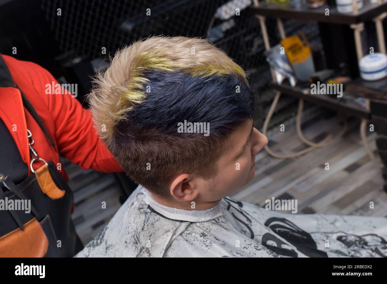 Junger Kunde im Friseursalon mit modischer Frisur und kreativer Haarfarbe im Friseursalon. Stockfoto