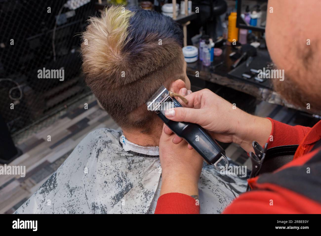 Die Hände eines Mannes, eines Meisters seiner Handwerkskunst, eines Friseurs, machen einen modischen, stilvollen Haarschnitt für einen jungen Mann, einen Kunden eines Friseurs. Stockfoto