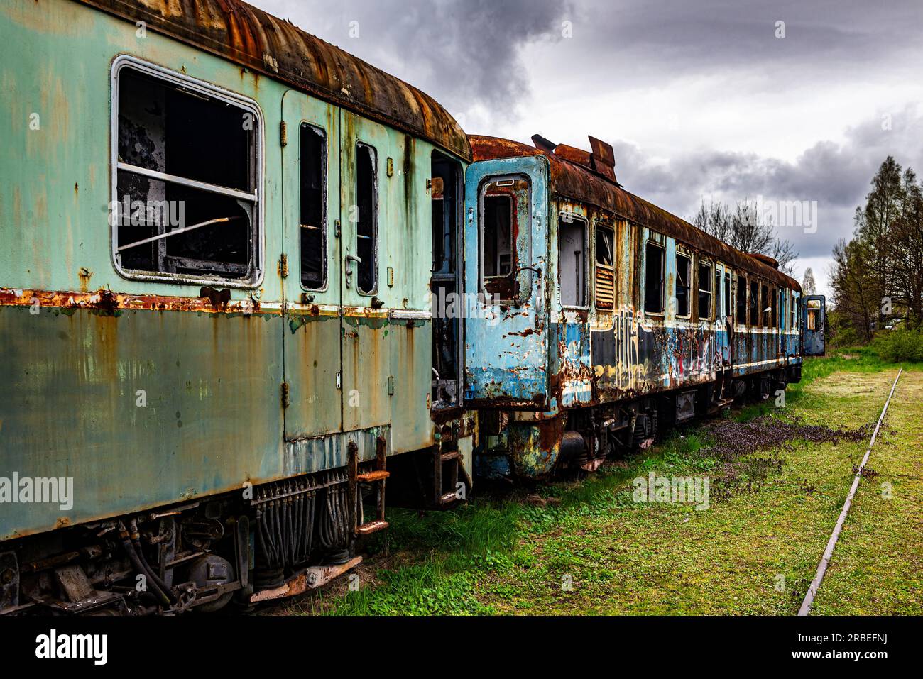 Der alte rostige elektrische Mehrzweckzug wurde stillgelegt und auf dem Bahngleis auf einem grünen Wiesenfeld aufgegeben Stockfoto