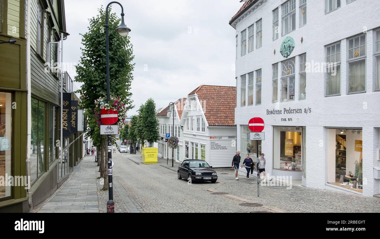 Blick auf eine ruhige, leere Straße mit traditionellen weißen Holzhäusern und moderneren Gebäuden und malerischen Geschäften entlang einer schmalen Straße Stockfoto