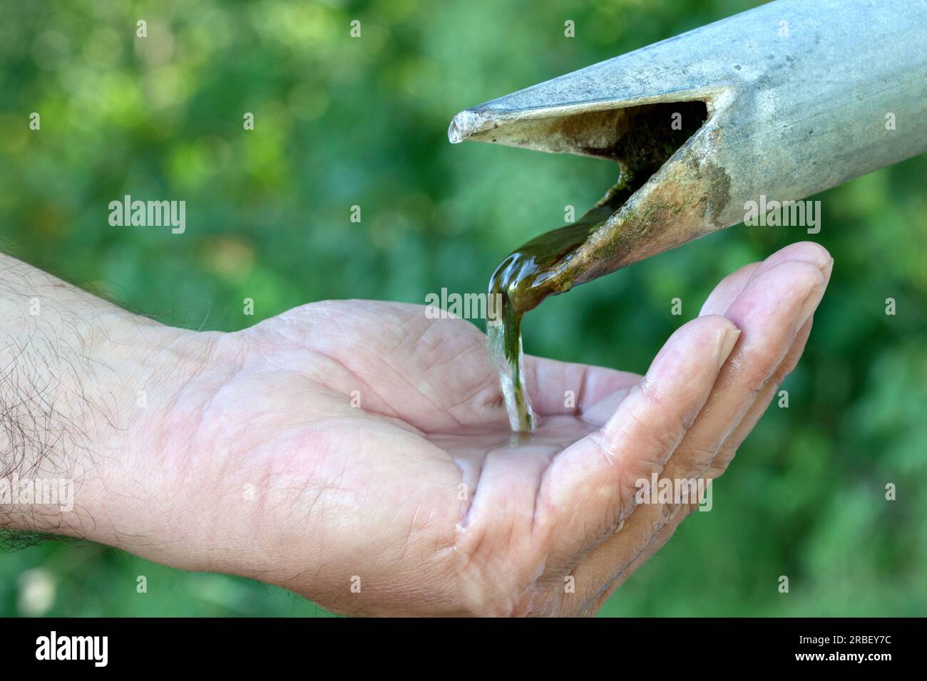 Nur ein wenig Wasser fließt aus dem Brunnen in die menschliche Hand. Stockfoto