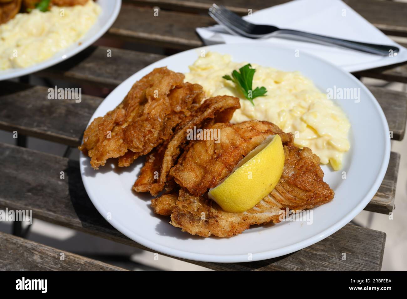 Frittierter Backfisch im Teig mit Hamburger Kartoffelsalat auf einem rustikalen Tisch Stockfoto