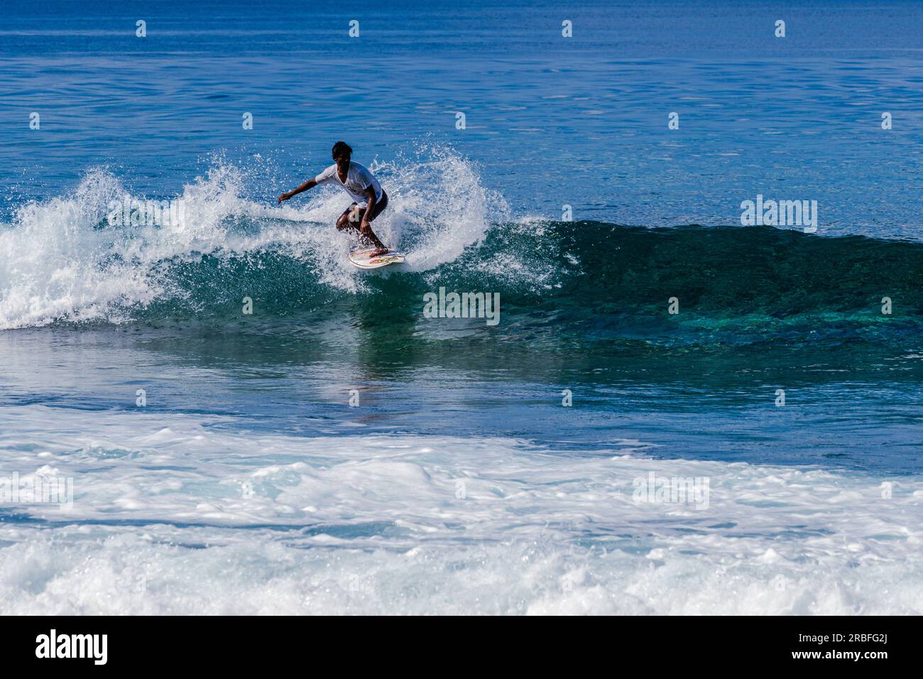 Malé Malediven--8. April 2023. Ein telephot-Bild eines Mannes, der surft und eine Welle am Pasta Point auf den Malediven fängt. Stockfoto