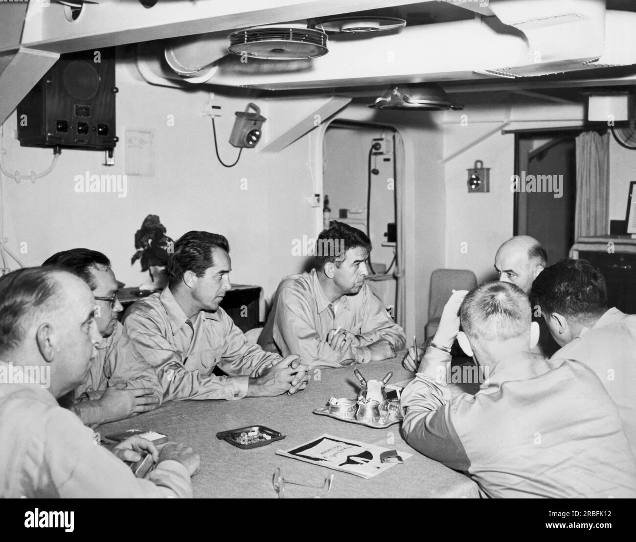 Korea: 18. Juli 1950 Kriegskorrespondenten hören Vizeadmiral Arthur Struble die Rolle der 7. Flotten bei Amphibienlandungen in Korea erklären. L-R sind Konteradmiral Hoskins; Melton Marmor, AP; David Douglas Duncan, Life Magazine; Harold Martin, Saturday Evening Post; Vizeadmiral Struble; Robert Martin, CBS; Und Larry Tighe, HOCH. Stockfoto