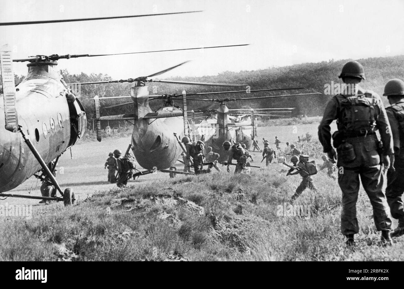 Vietnam: 25. Oktober 1962 amerikanische Berater beobachten, wie vietnamesische Truppen an Bord von Hubschraubern für eine Anti-Vietcong-Operation in den Dschungeln bei Saigon Rennen. Stockfoto