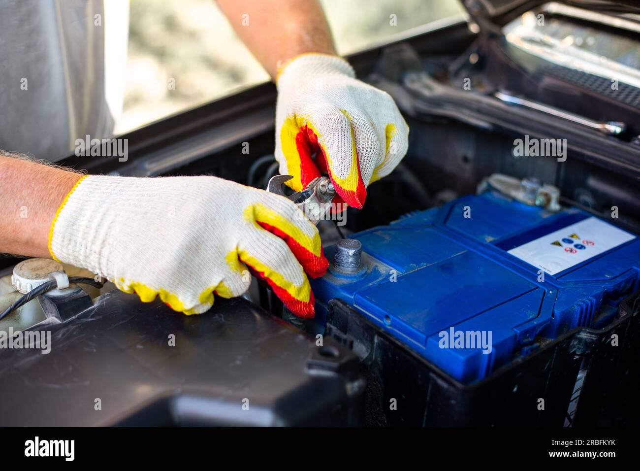 Austausch der Autobatterie. Der Mechaniker entfernt die Klemmen aus dem Batteriegehäuse. Stockfoto