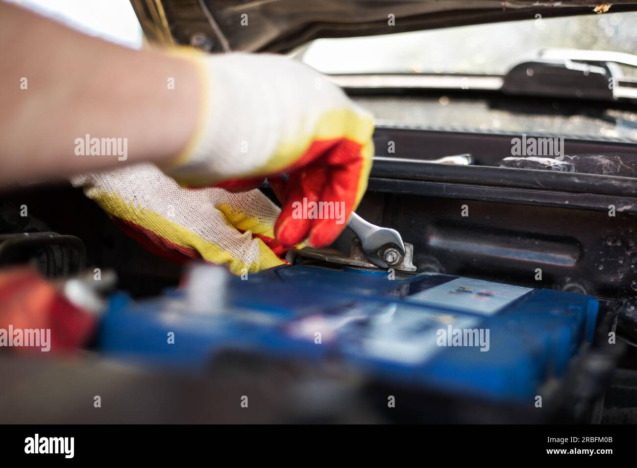 Austausch der Autobatterie. Der Mechaniker entfernt die Klemmen aus dem Batteriegehäuse. Stockfoto