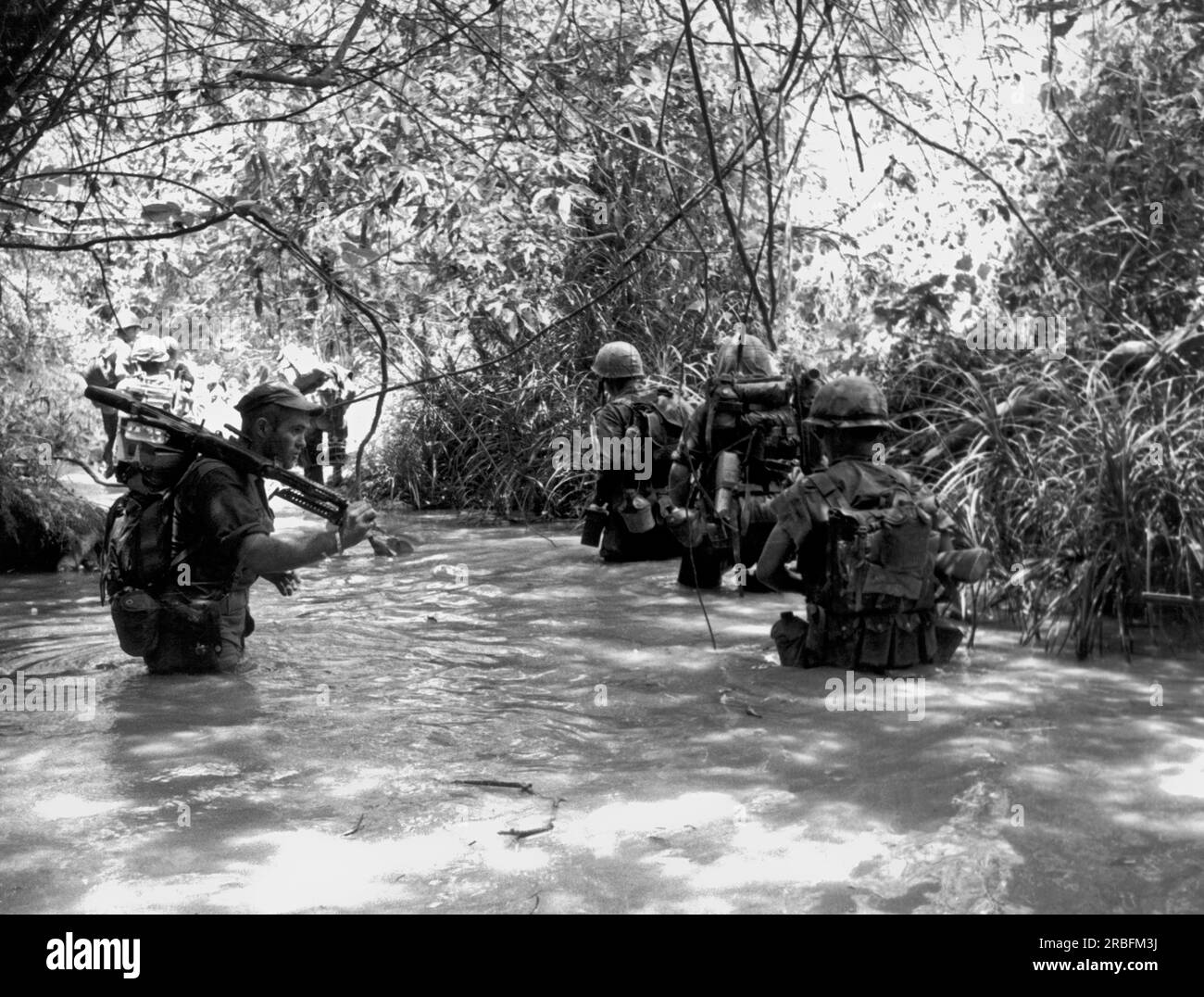 Vietnam: 12. August 1966 Marines of H Company, 4. Marine Regiment, umgehen Sie den dichten Dschungel und nutzen Sie einen Bach für eine Wanderung, während Sie sich während der Operation Hastings der nordvietnamesischen 324. Division stellen. Stockfoto