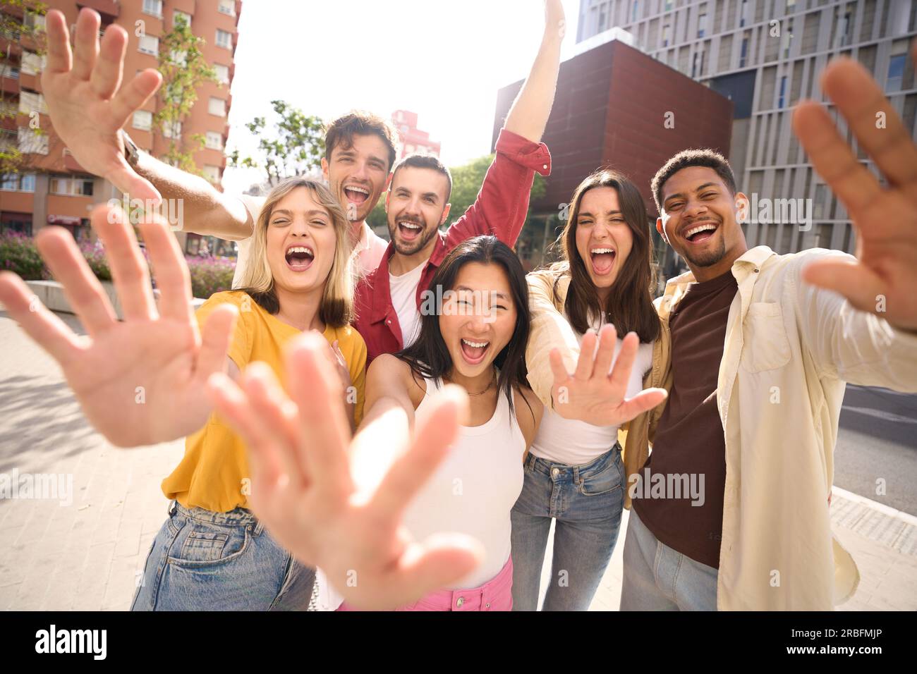 Fröhliche, multikulturelle Gruppenfreunde, die mit Freude vor der Kamera winken. Portrait begeisterte fröhliche junge Leute Stockfoto