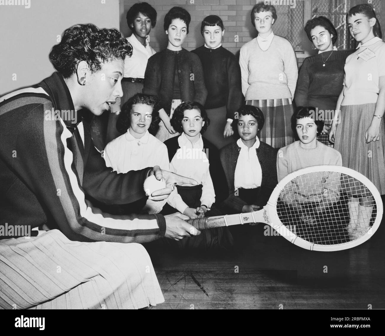 New York, New York: Dezember 1957 Althea Gibson, US- und Wimbledon-Tennismeisterin, gibt Schülern, die eine Tennisklinik an der Midwood High School in Brooklyn besuchen, einige Hinweise zum Spiel. Stockfoto