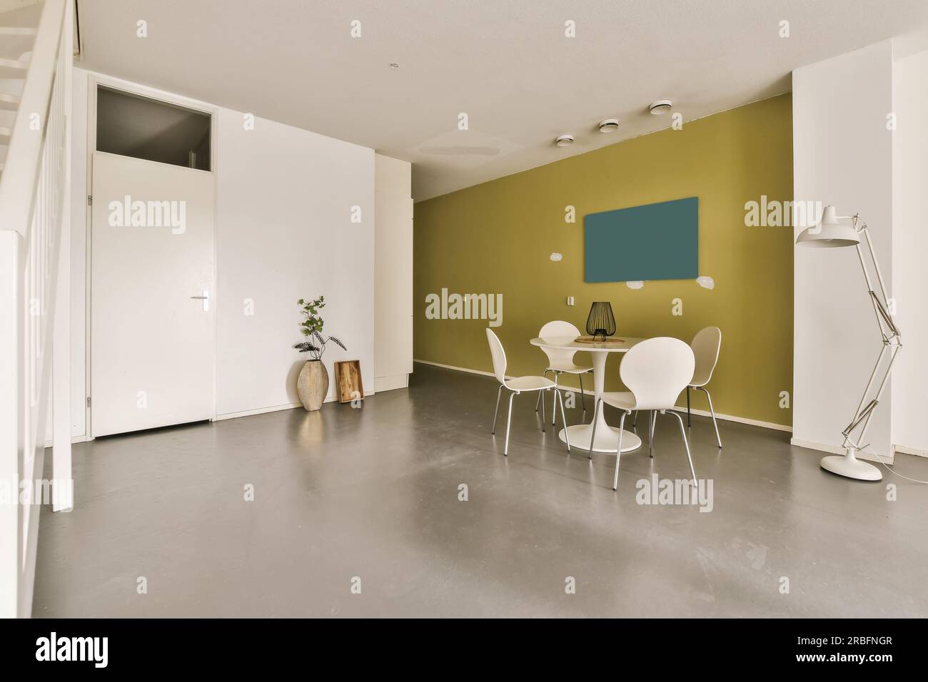 Ein Wohnzimmer mit grünen Wänden und weißen Möbeln auf dem Boden, es gibt eine offene Tür, die zu einem anderen Zimmer führt Stockfoto