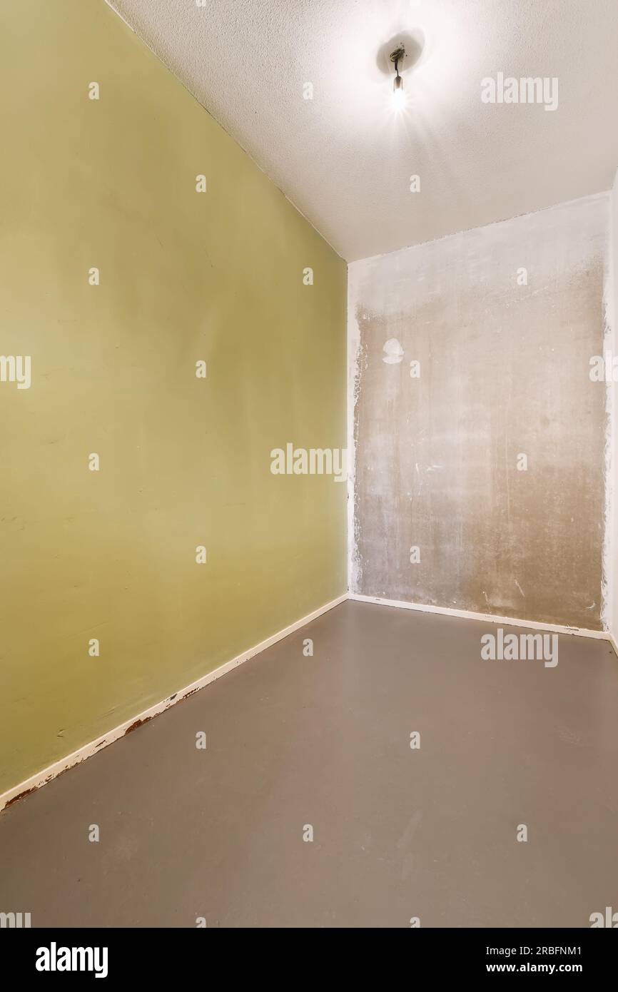 Ein leerer Raum mit grünen Wänden und weißer Farbe an den Wänden und eine kleine Leuchte in der Ecke Stockfoto