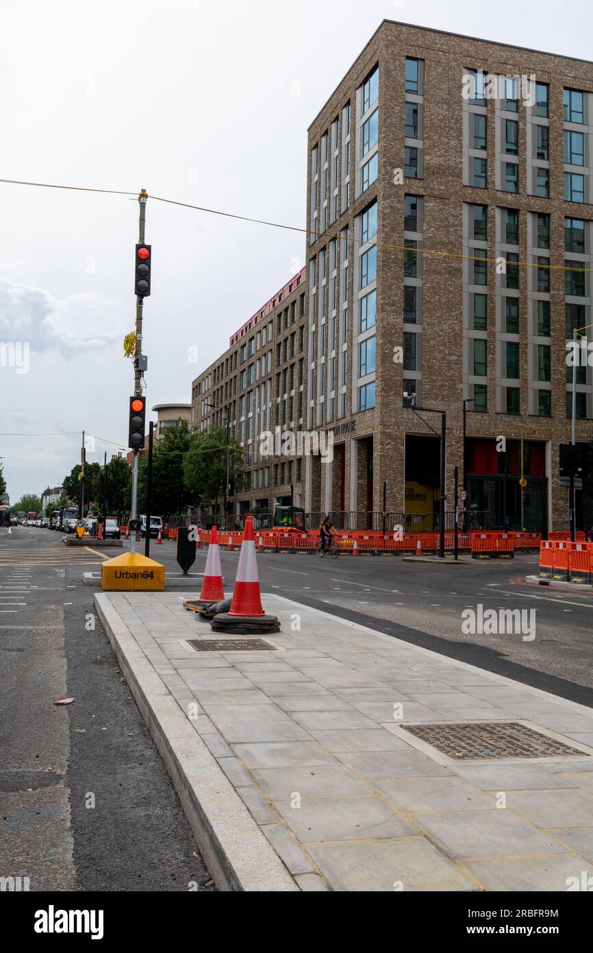 Straße/Straße wird gewartet. Temporäre Ampel. Straßenarbeiten orangefarbener Zaun/Barrieren und Kegel. Stockfoto