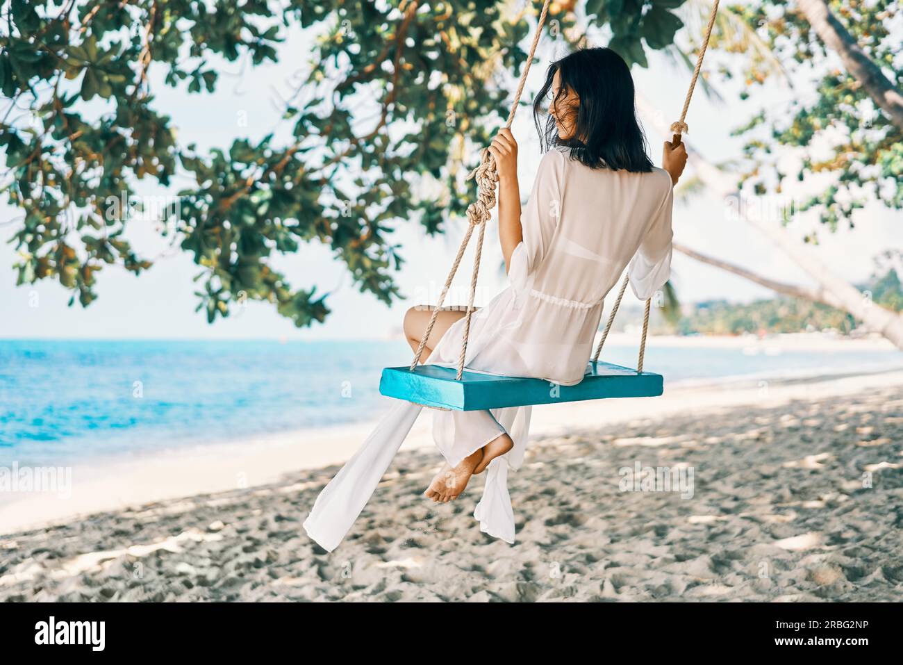 Sorglos glücklich Frau auf Schwingen auf schöne Paradiese Strand. Entspannung und Freiheit Konzept Stockfoto