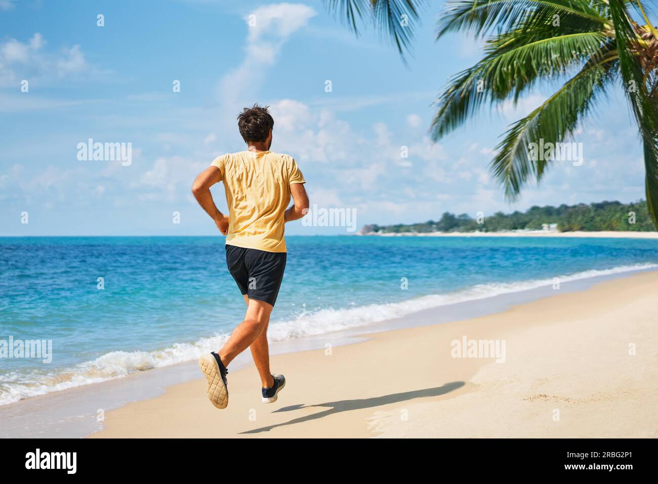 Rückansicht des laufender Mann am tropischen Strand. Gesunder Lebensstil und Sport Konzept Stockfoto