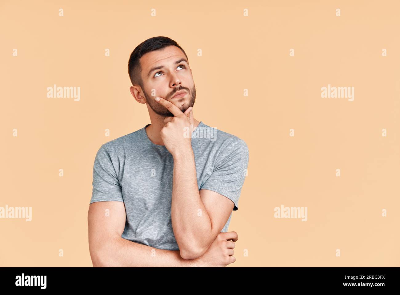 Junge nachdenkliche Menschen denken und neben der Suche auf copy Speicherplatz auf gelben Hintergrund. Männliche Hand am Kinn. Zweifel, Lösung, Entscheidung und Stockfoto