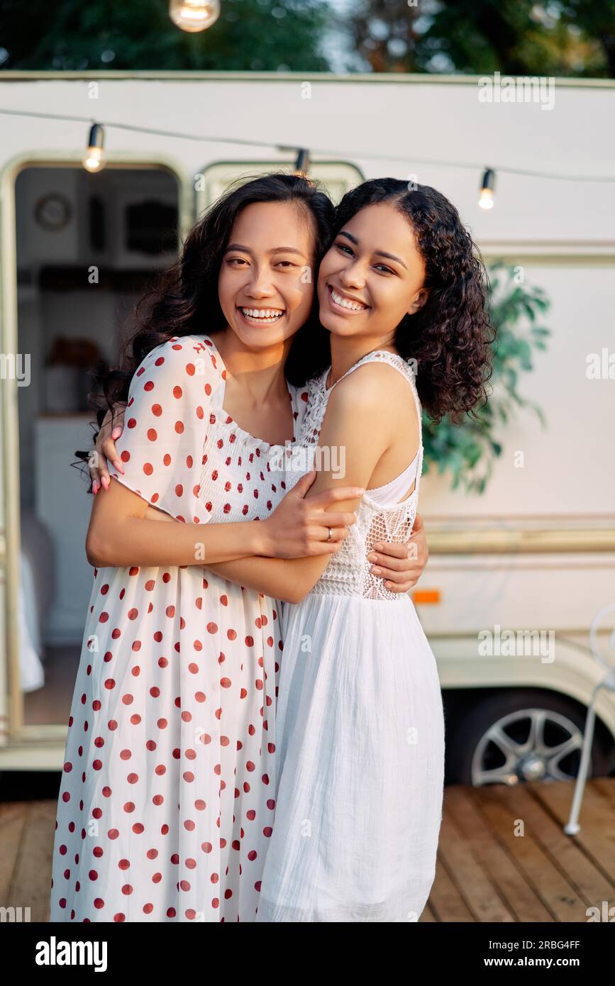 Glücklich lächelnde Asiaten und Afro-amerikanische Frau umarmen und haben eine tolle Zeit zusammen. Frauen Freundschaft Konzept. Zwei beste Freunde, die im Freien Stockfoto