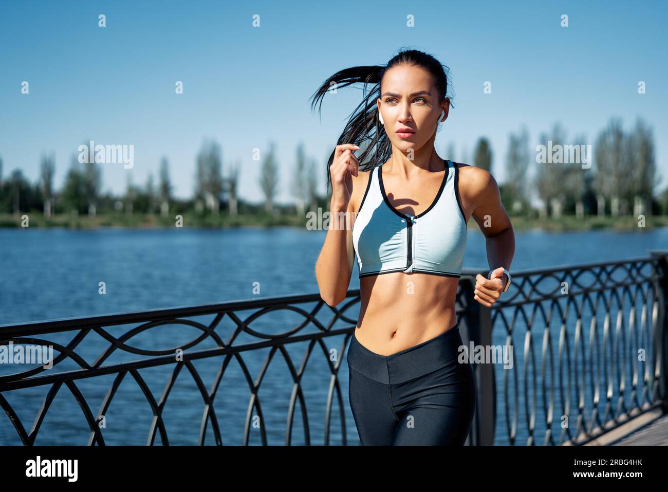 Junge Fitness-Frau, die am Flussufer läuft. Gesunder Lebensstil Stockfoto