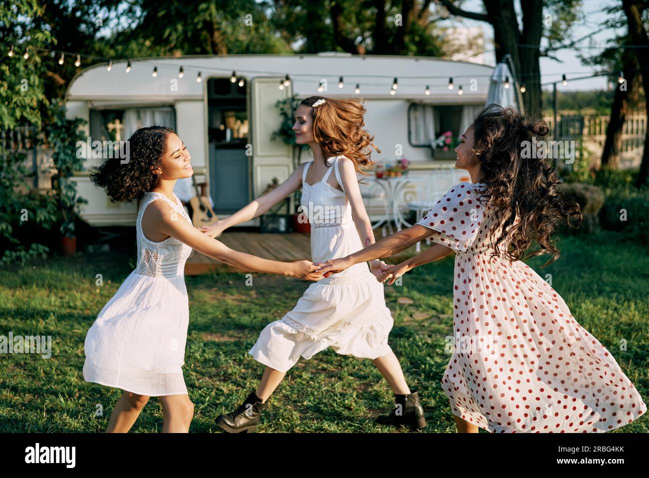 Gerne schöne Frauen tanzen im Kreis während ein Picknick. Multi-ethnische Mädchen Spaß zusammen haben im Freien. Kaukasier, afrikanische amerikanische und asiatische Mädchen Stockfoto